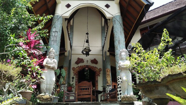 A traditional building with a clock, columns, and a wooden door. - Puri Eling Blimbingsari (Melaya)