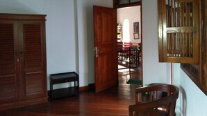 A hallway with wooden doors, a small table, and a chair. - Puri Eling Blimbingsari (Melaya)