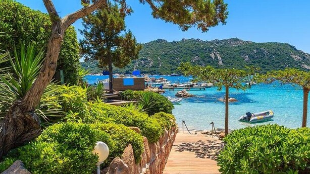A coastal resort with a wooden deck leading to a beach, surrounded by lush greenery and clear blue waters. - Magnificent T2 on the ground floor with pool in Alata in southern Corsica (Alata)