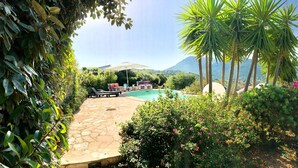 A pool area with lounge chairs and a stone patio, surrounded by lush greenery and palm trees. - Magnificent T2 on the ground floor with pool in Alata in southern Corsica (Alata)
