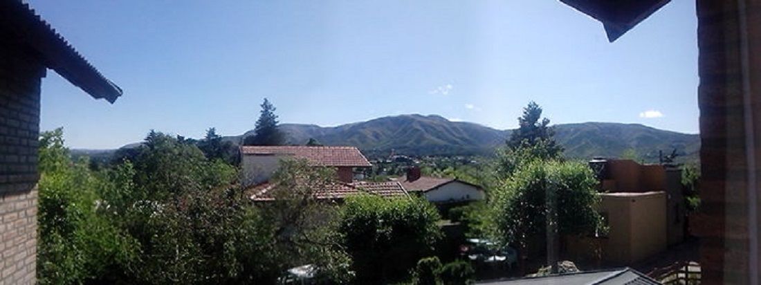 Un barrio residencial con casas, árboles y montañas al fondo.