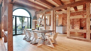 A modern dining area with a wooden ceiling, a large window, and a brick wall. - Backsteinspeicher Stralsund (Stralsund)