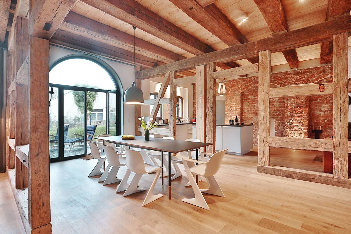 Un comedor moderno con techo de madera, un ventanal grande y una pared de ladrillo.