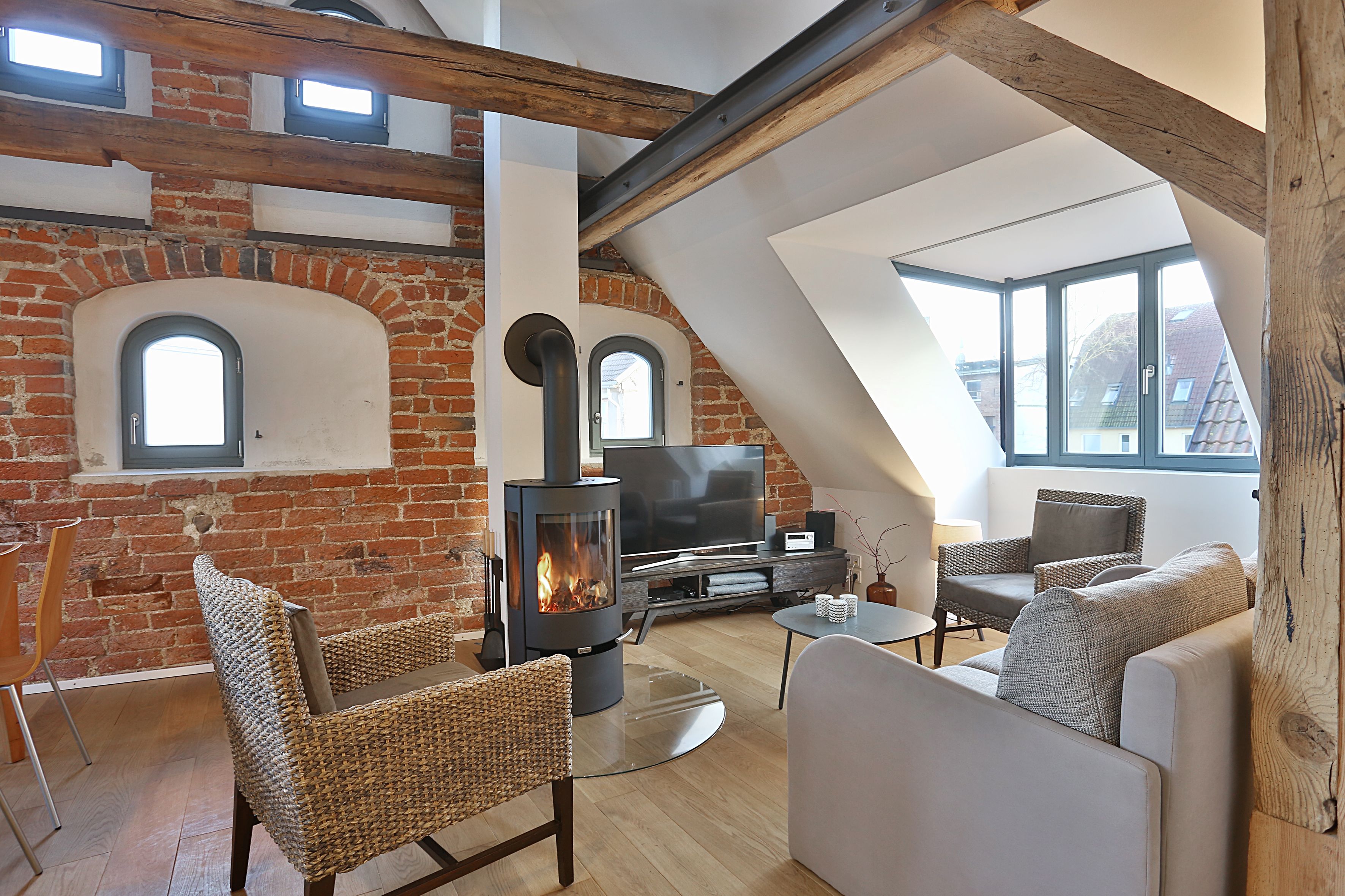 Ein Loft-Wohnzimmer mit freiliegenden Backsteinwänden, einem großen Kamin und einem modernen Sofa.