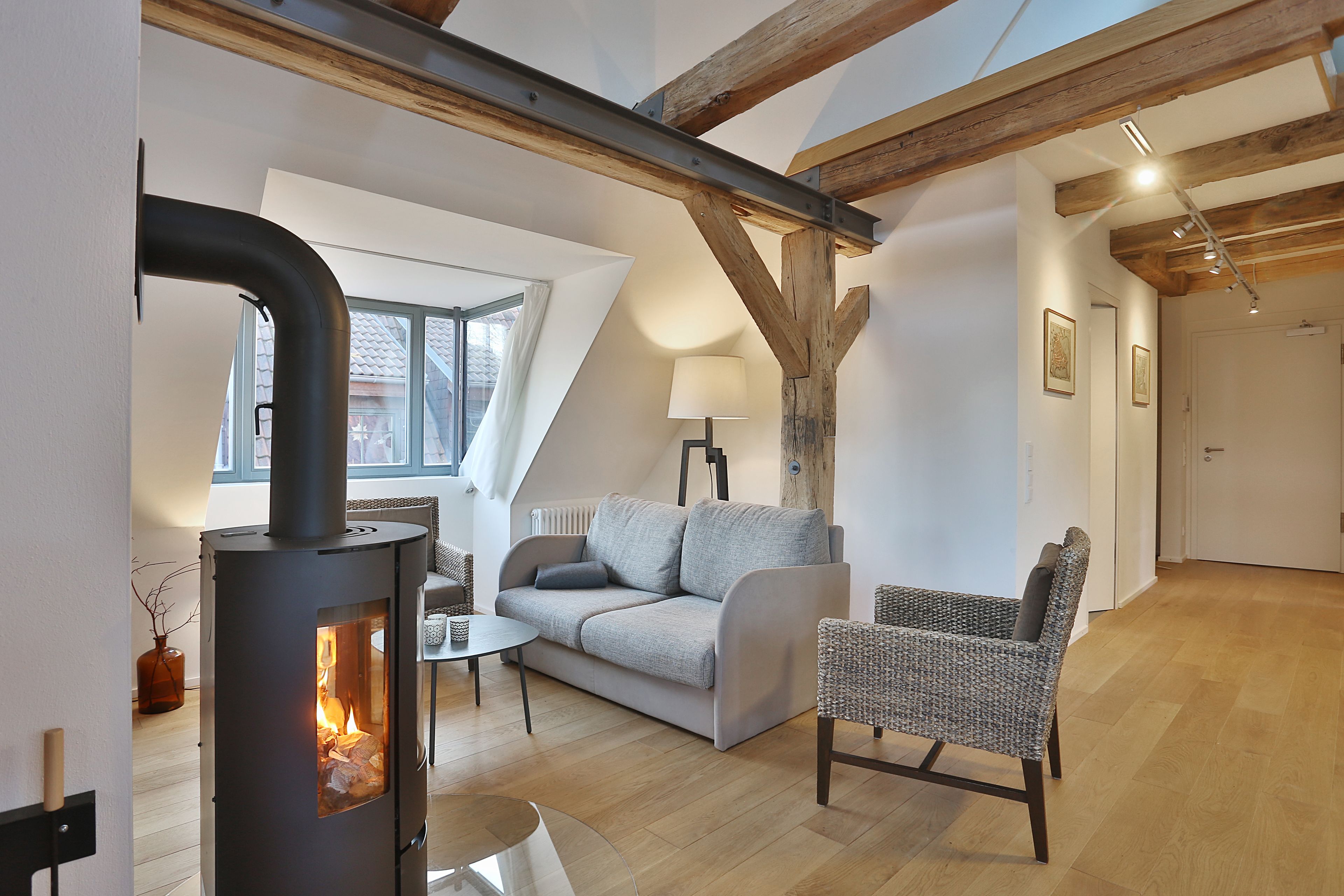 Ein gemütliches Wohnzimmer mit Kamin, einer Couch, einem Sessel und einem Esstisch.