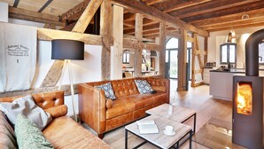 A cozy living room with a leather sofa, a coffee table, and a wood-burning stove. - Backsteinspeicher Stralsund (Stralsund)