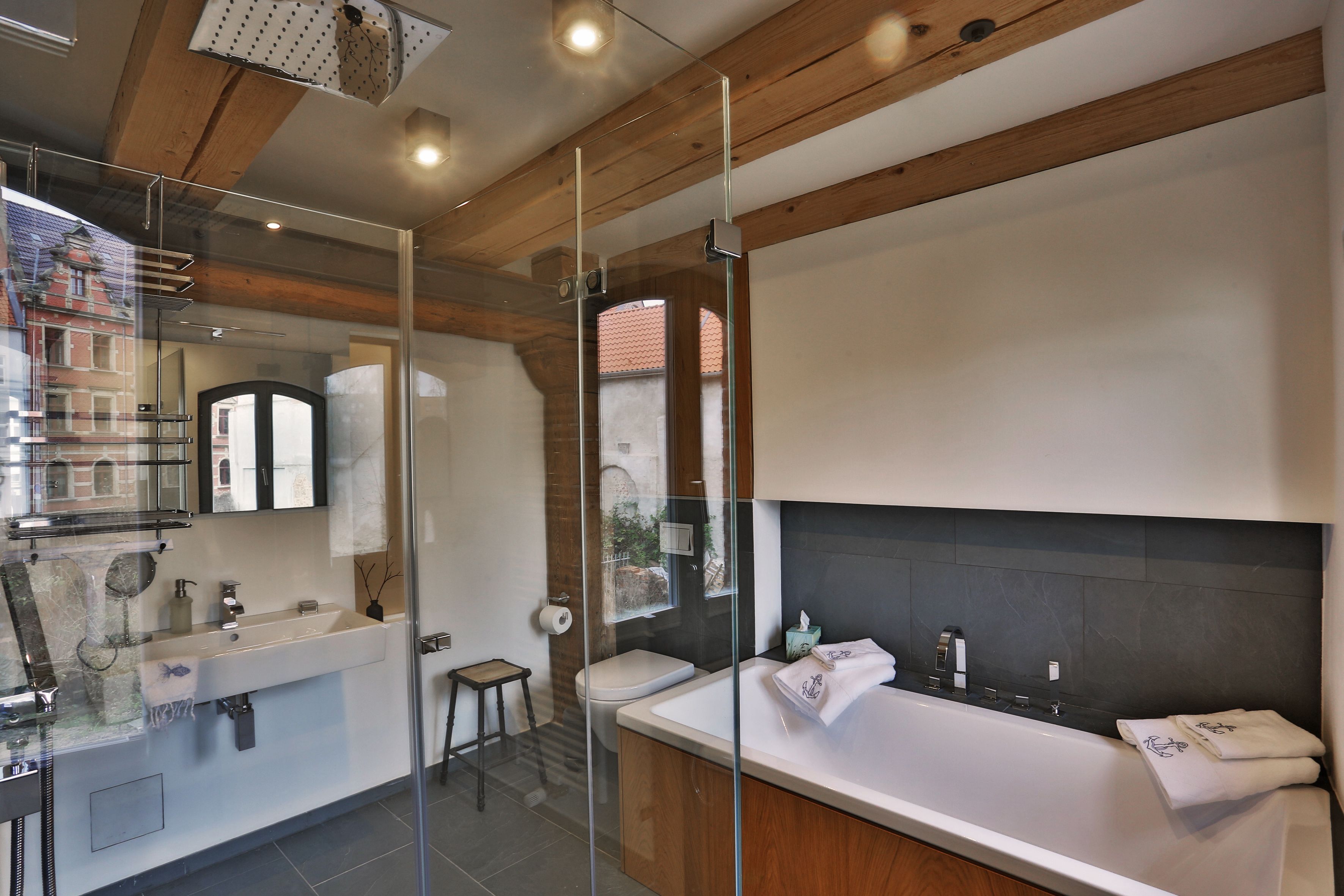 A modern bathroom with a glass-enclosed shower, a large bathtub, and a separate sink area.