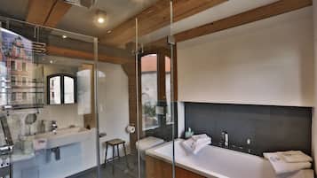 A modern bathroom with a glass-enclosed shower, a large bathtub, and a separate sink area.