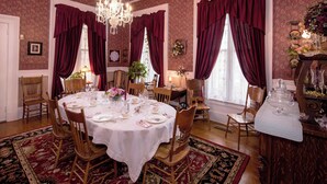 Un comedor formal con una mesa redonda preparada para seis personas, rodeada de sillas de madera.