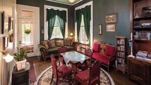 Un salón acogedor con una mesa redonda, sillas rojas, un sofá y una estantería.