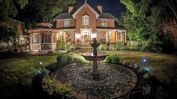 Una casa grande e histórica con un jardín cuidado y un pabellón.