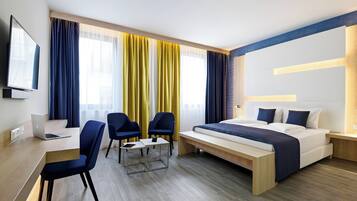 Een moderne hotelkamer met een bed, bureau, stoelen en een televisie.