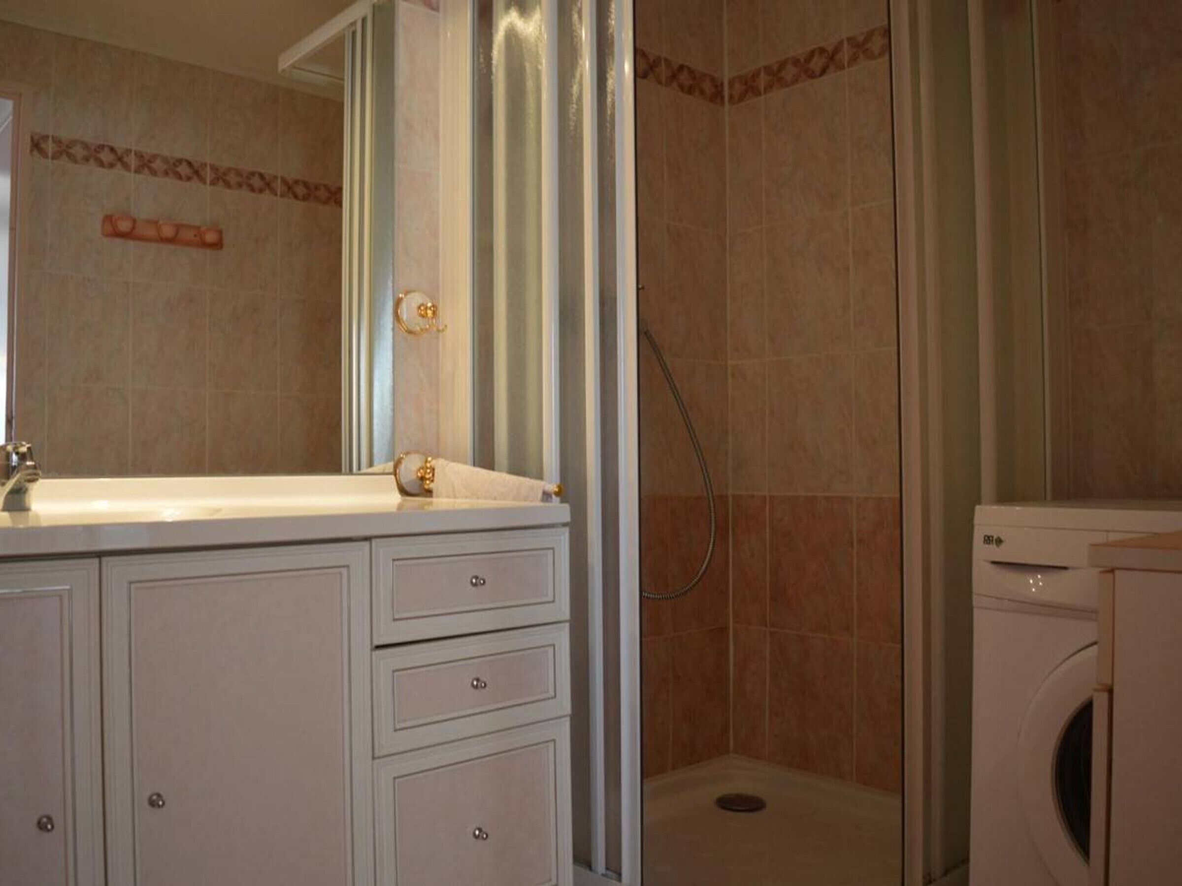 Une salle de bain avec une douche, un lavabo et un lave-linge.
