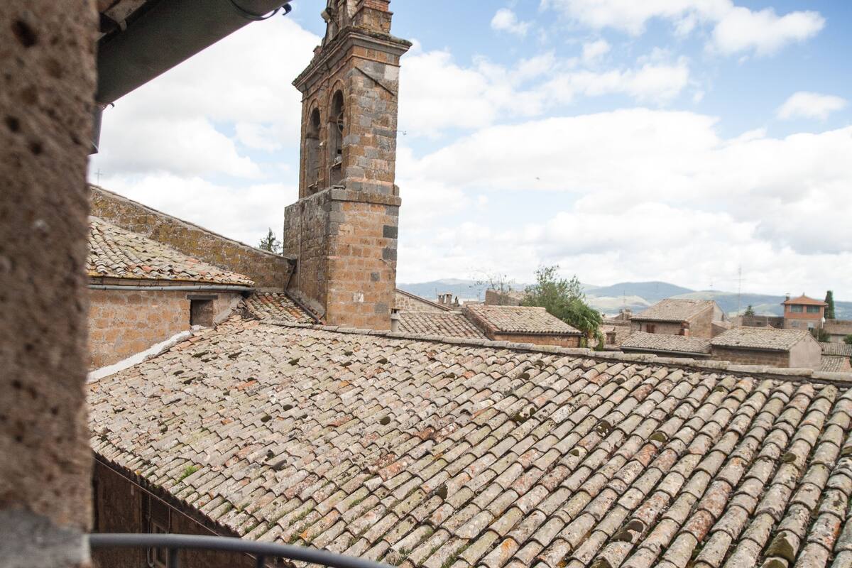 A view of a historic building with a tiled roof and a prominent tower.