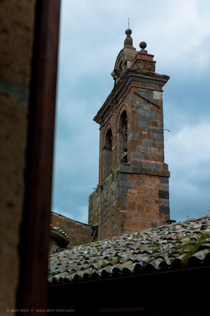 Een hoge, historische stenen toren met boogvensters en een verweerd dak.