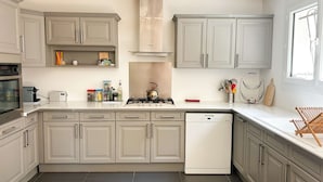A modern kitchen with grey cabinets, a built-in oven, a dishwasher, and a gas stove.