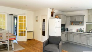 A modern kitchen with grey cabinets, a white refrigerator, and a dining area with a striped tablecloth.
