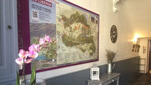 A reception area with a large map, a clock, and a small table with a sign. - Luberon L'hôtel (Apt)