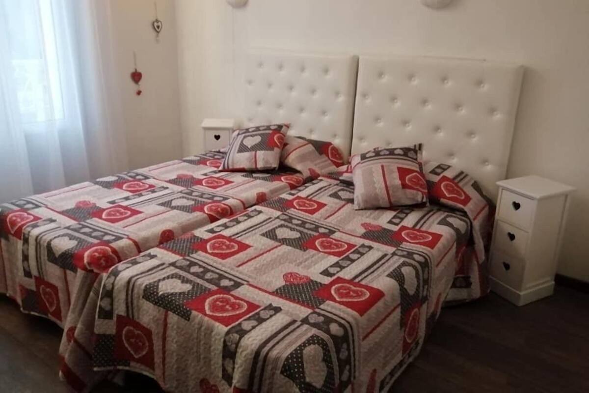 Quarto com uma cama grande, cabeceira branca e duas mesas de cabeceira.