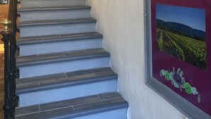 A staircase with a handrail, a door at the top, and a framed sign on the wall reading "Hotel". - Luberon L'hôtel (Apt)