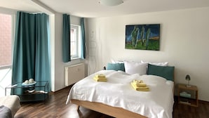 Een keurig opgemaakt slaapkamer met een groot bed, een nachtkastje, een stoel en een raam met gordijnen.