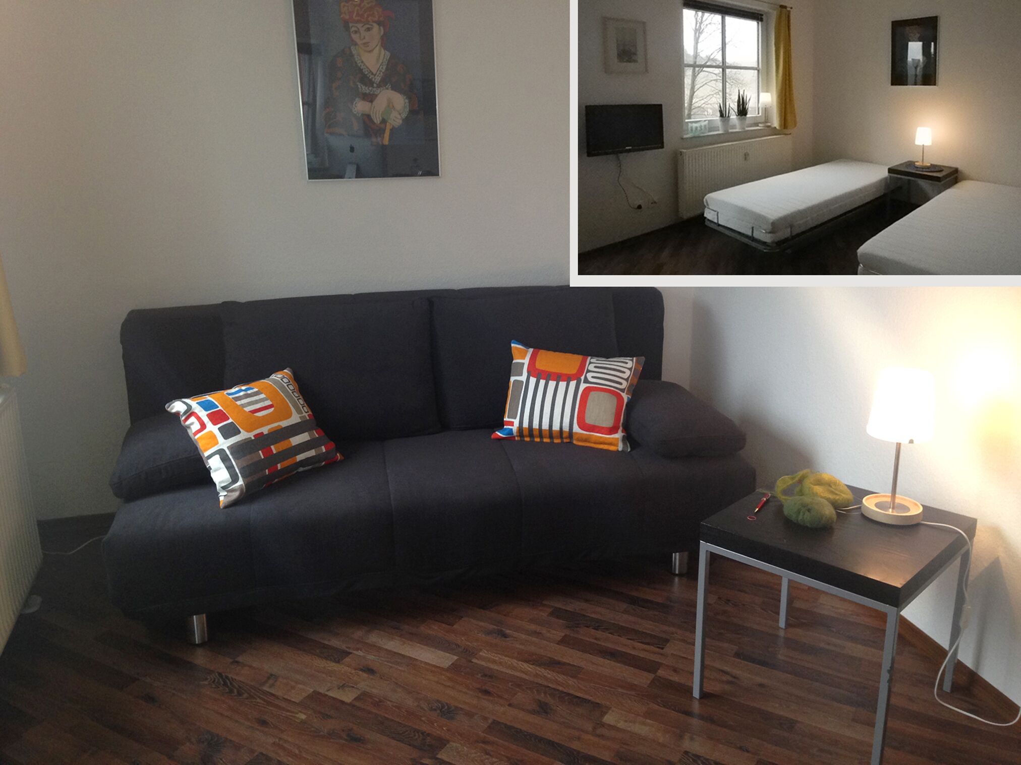 Ein modernes Wohnzimmer mit einem dunklen Sofa, farbenfrohen Kissen, einem kleinen Tisch mit Lampe und Holzboden.