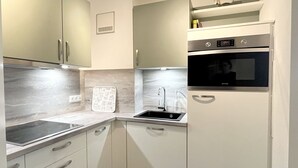 Een kleine keuken met een ingebouwde oven, een spoelbak en een aanrecht.