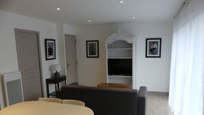 Una sala de estar moderna con una mesa de comedor, sofá y mueble para televisión.