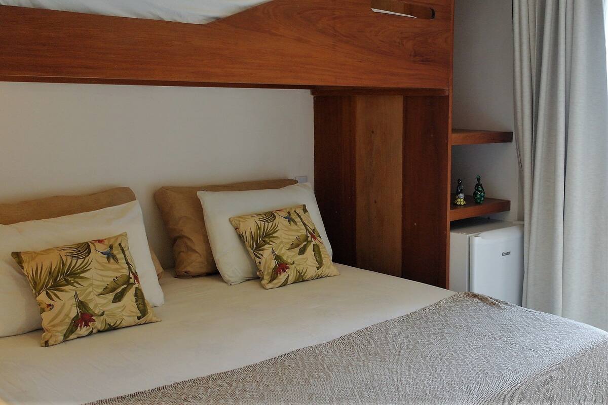 A bunk bed with two pillows, a small shelf, and a refrigerator.