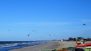 Une plage avec des gens, des cerfs-volants et des bateaux.