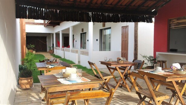 Un espace extérieur aménagé en terrasse, avec des tables et des chaises en bois, dont certaines sont dressées pour le petit-déjeuner.