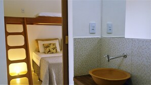 Une chambre avec un lit superposé, une table de chevet et une petite fenêtre.