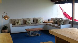 Un salon avec un canapé, une table basse en bois et un hamac.