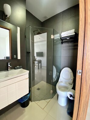 Une salle de bain moderne avec une douche à parois de verre, un lavabo blanc et des toilettes.