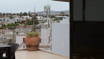 A balcony with a potted plant, a table, and chairs.