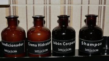 Cuatro botellas de artículos de aseo personal con la etiqueta 'Suites La Gloria Hotel'.