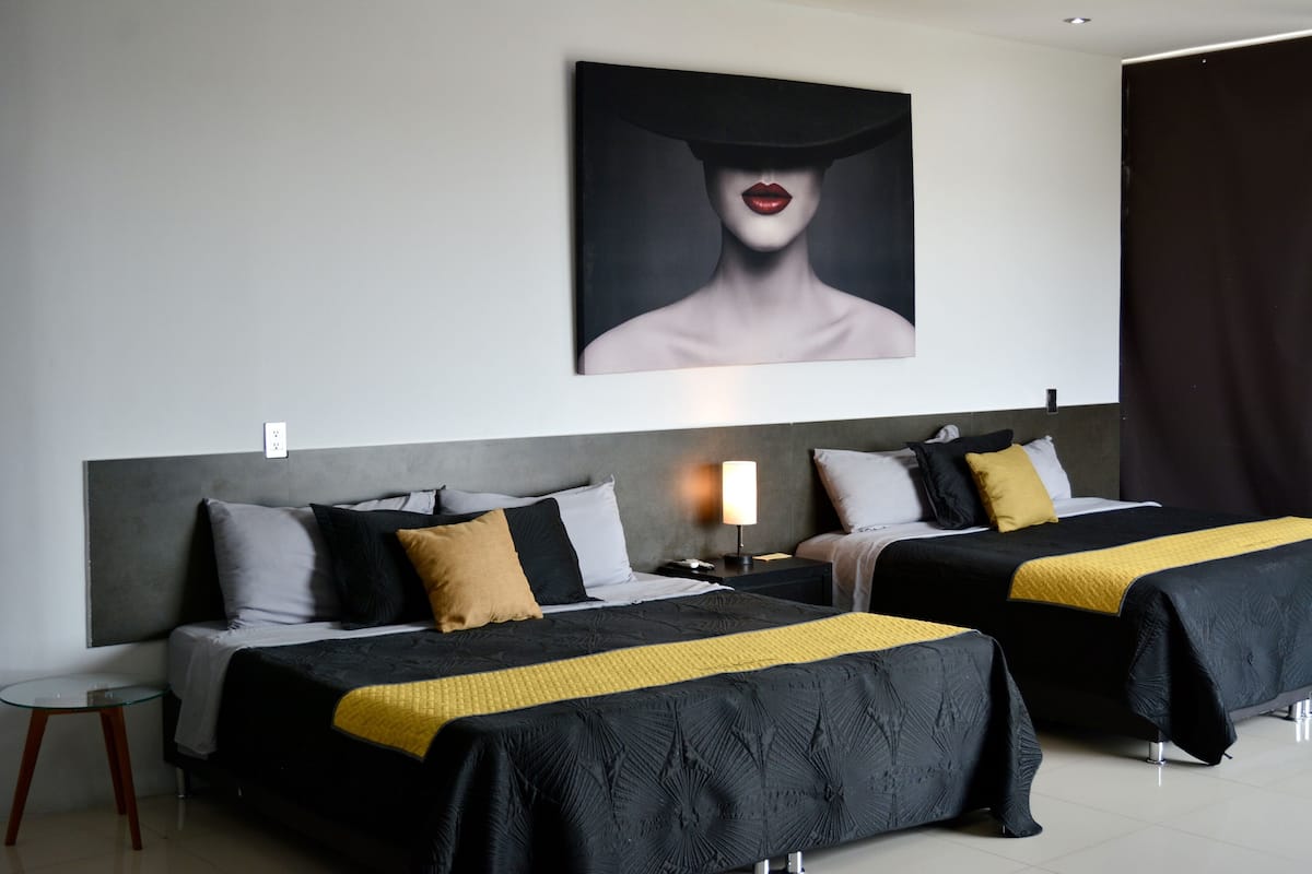 Een hotelkamer met twee bedden, een nachtkastje, een tafeltje en een schilderij aan de muur.