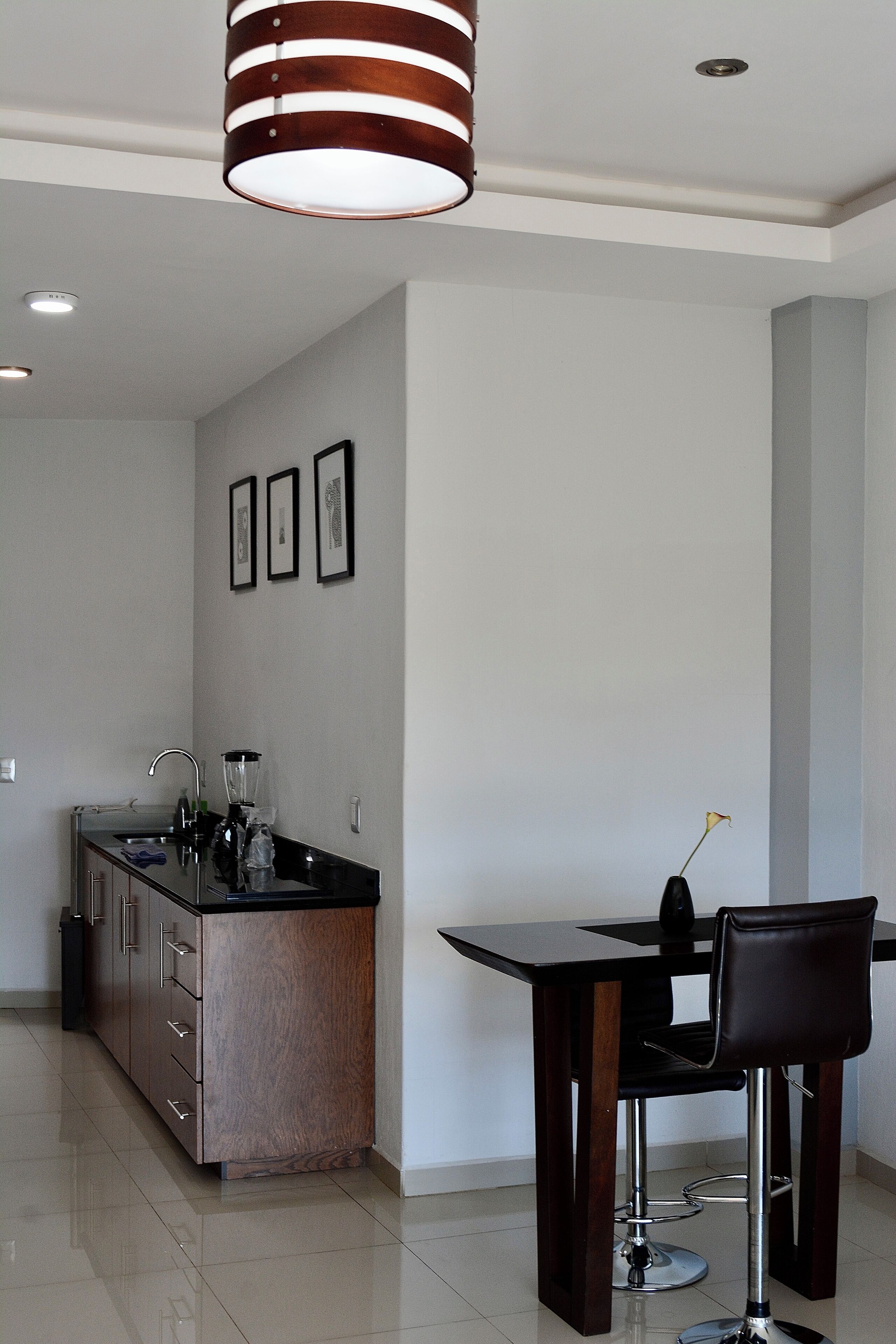 A modern kitchen with a dining area, featuring a kitchen island, bar stools, and pendant lighting.