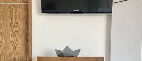 A wooden dresser with drawers and a flat-screen TV mounted on the wall above it.