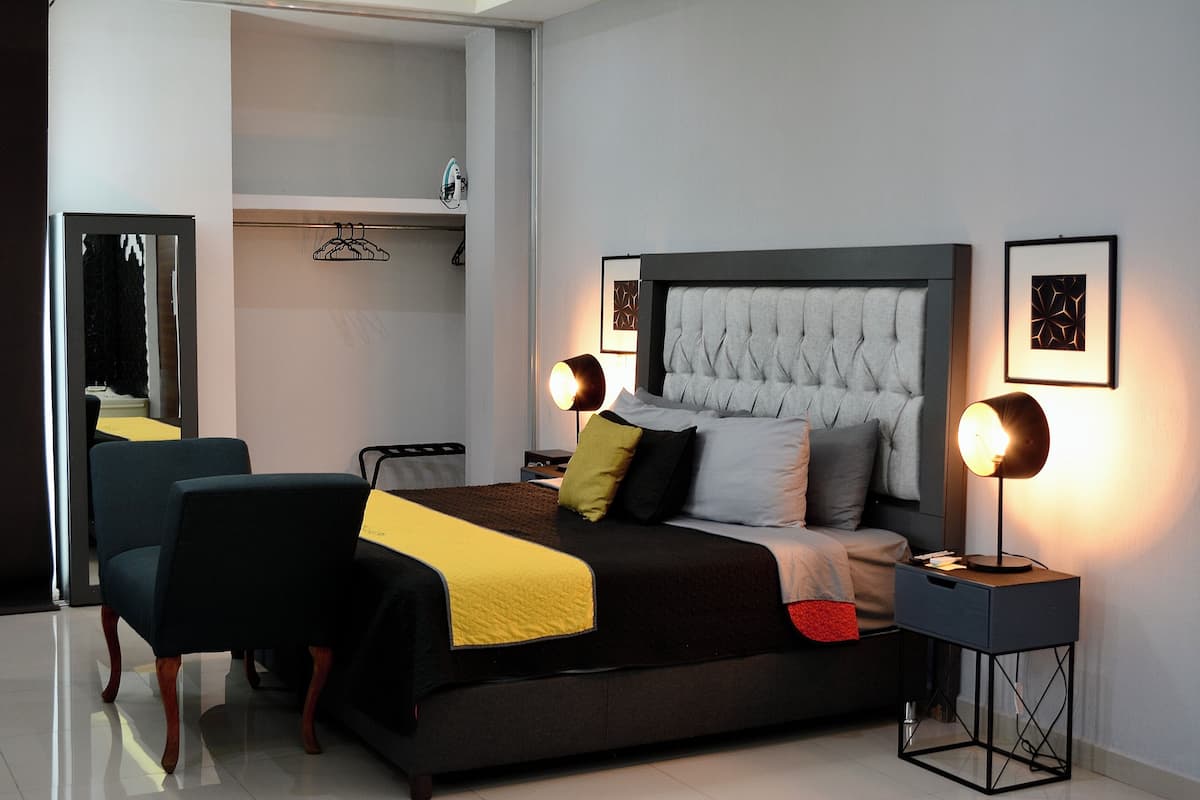 Een moderne slaapkamer met een groot bed, nachtkastjes, een stoel en een kledingkast.