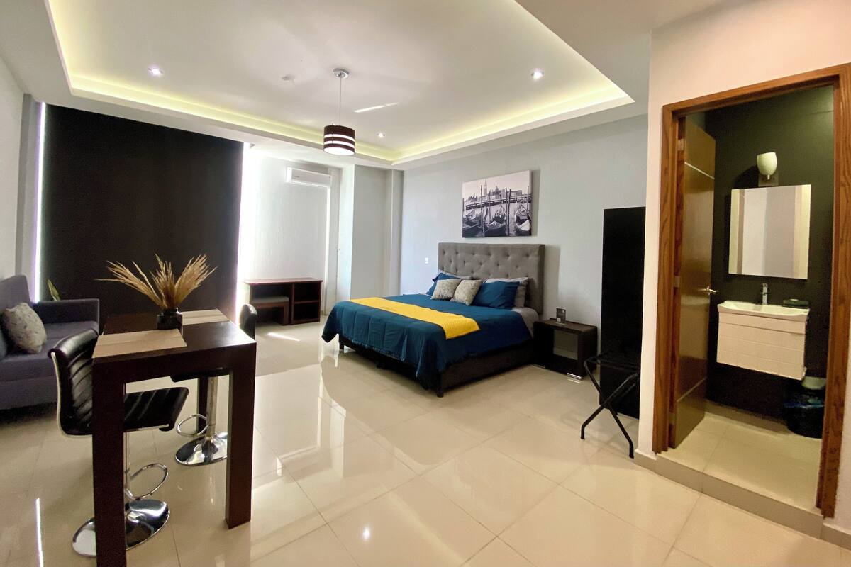 Een moderne hotelkamer met een groot bed, een bureau, een stoel, een televisie en een badkamer.