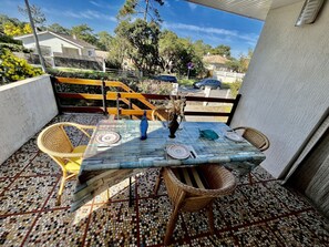 Eine Terrasse mit Mosaikfliesen, einem Esstisch, Korbstühlen und Blick auf die Nachbarschaft.