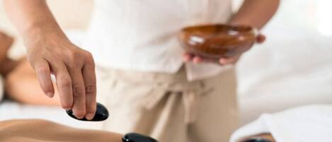 Eine Person führt eine Therapie mit einem Klienten durch, der auf einer Massageliege liegt und dabei ein therapeutisches Gerät am Rücken des Klienten einsetzt.