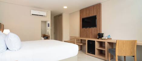 Een hotelkamer met een bed, een bureau, een stoel, een televisie en een airconditioner.