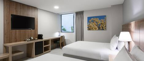 Une chambre d’hôtel avec un lit, un bureau, une télévision et une fenêtre avec des rideaux.