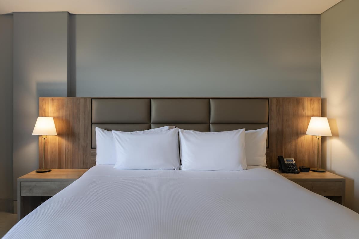 A neatly made bed with white linens, two bedside lamps, and a telephone on each nightstand.