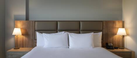 A neatly made bed with white linens, two bedside lamps, and a telephone on each nightstand.
