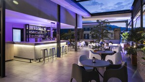 An outdoor bar area with a glass ceiling, seating, and a bar counter. - Hilton Garden Inn Cali Ciudad Jardin (Cali)