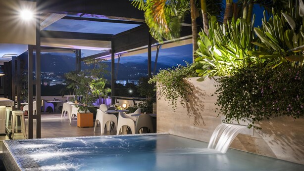 A rooftop pool with a waterfall, surrounded by outdoor seating and lush greenery. - Hilton Garden Inn Cali Ciudad Jardin (Cali)