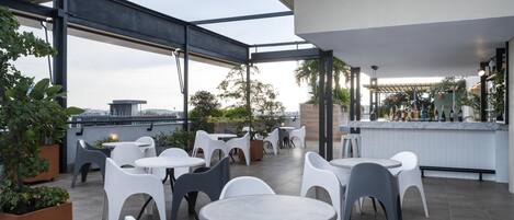 A rooftop terrace with outdoor seating, a bar area, and potted plants.